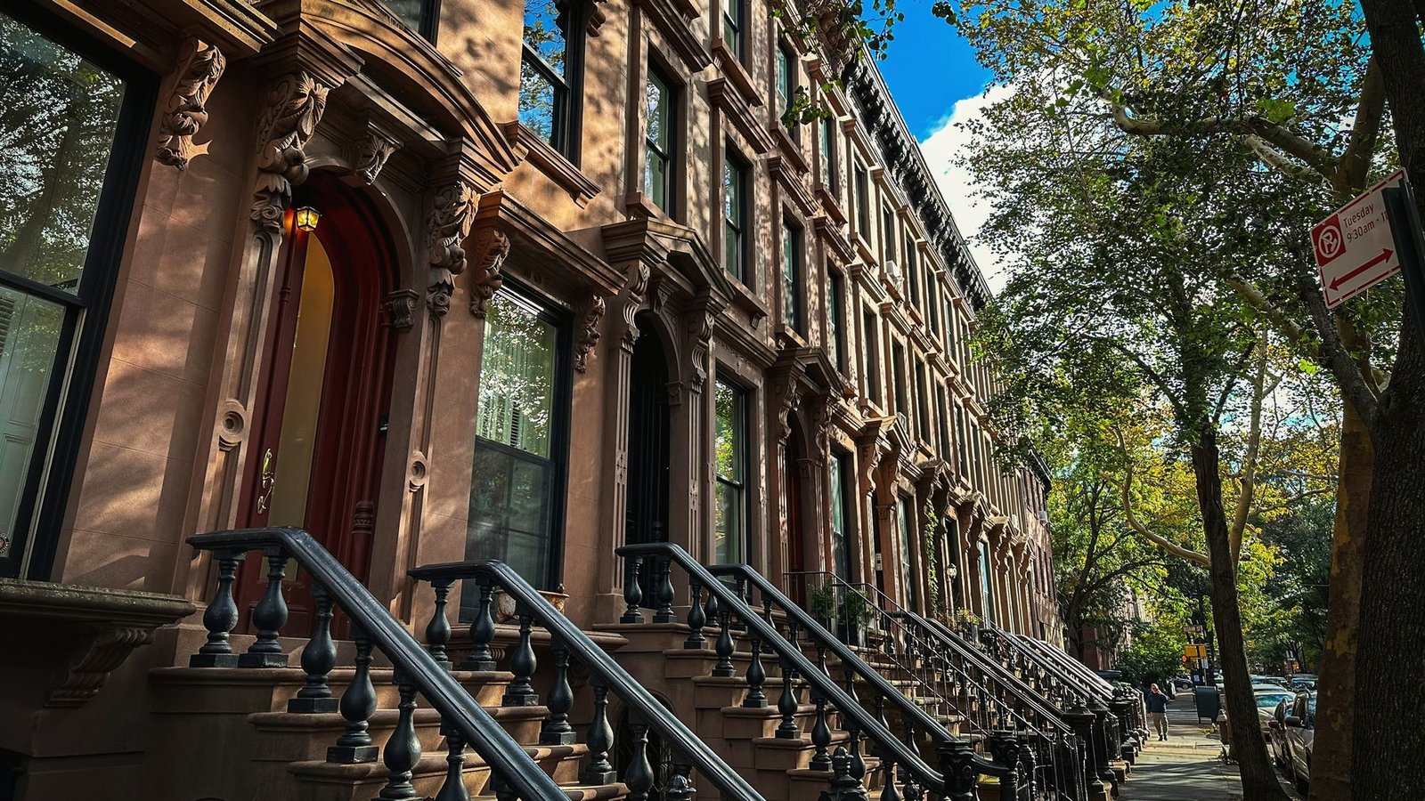 A row of Brooklyn brownstones with cast-iron stoop railings in warm afternoon light