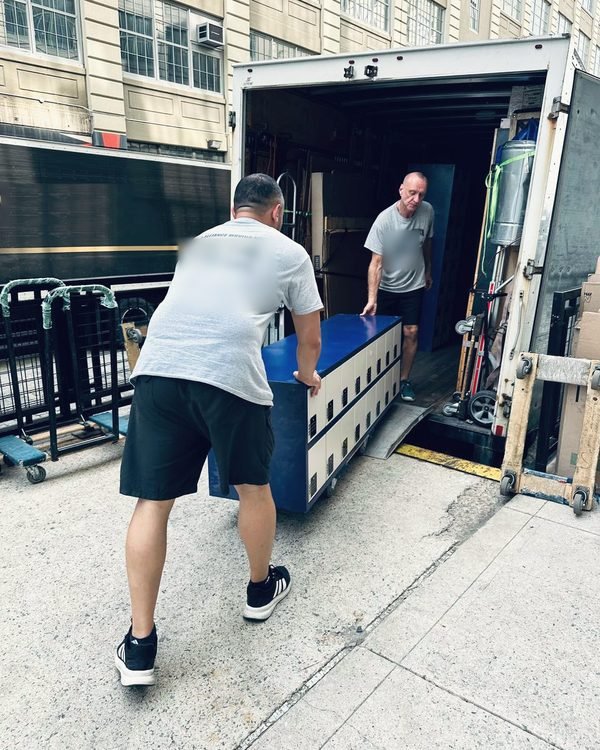 Two movers loading a bank of office lockers into our truck at a commercial building