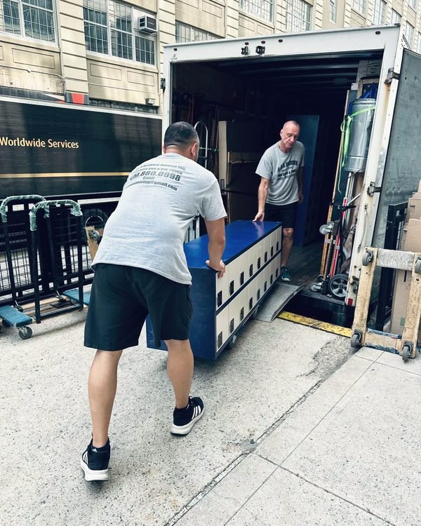 Two movers loading a bank of office lockers into our truck at a commercial building