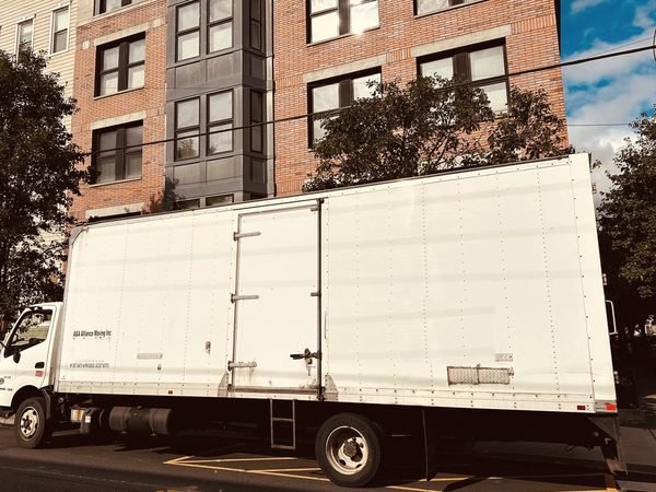 Our box truck parked on a city block of brick and siding walk-ups