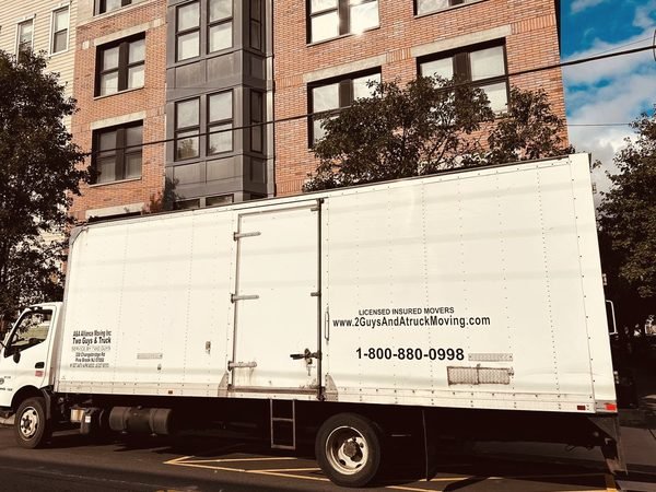 Our box truck parked on a city block of brick and siding walk-ups